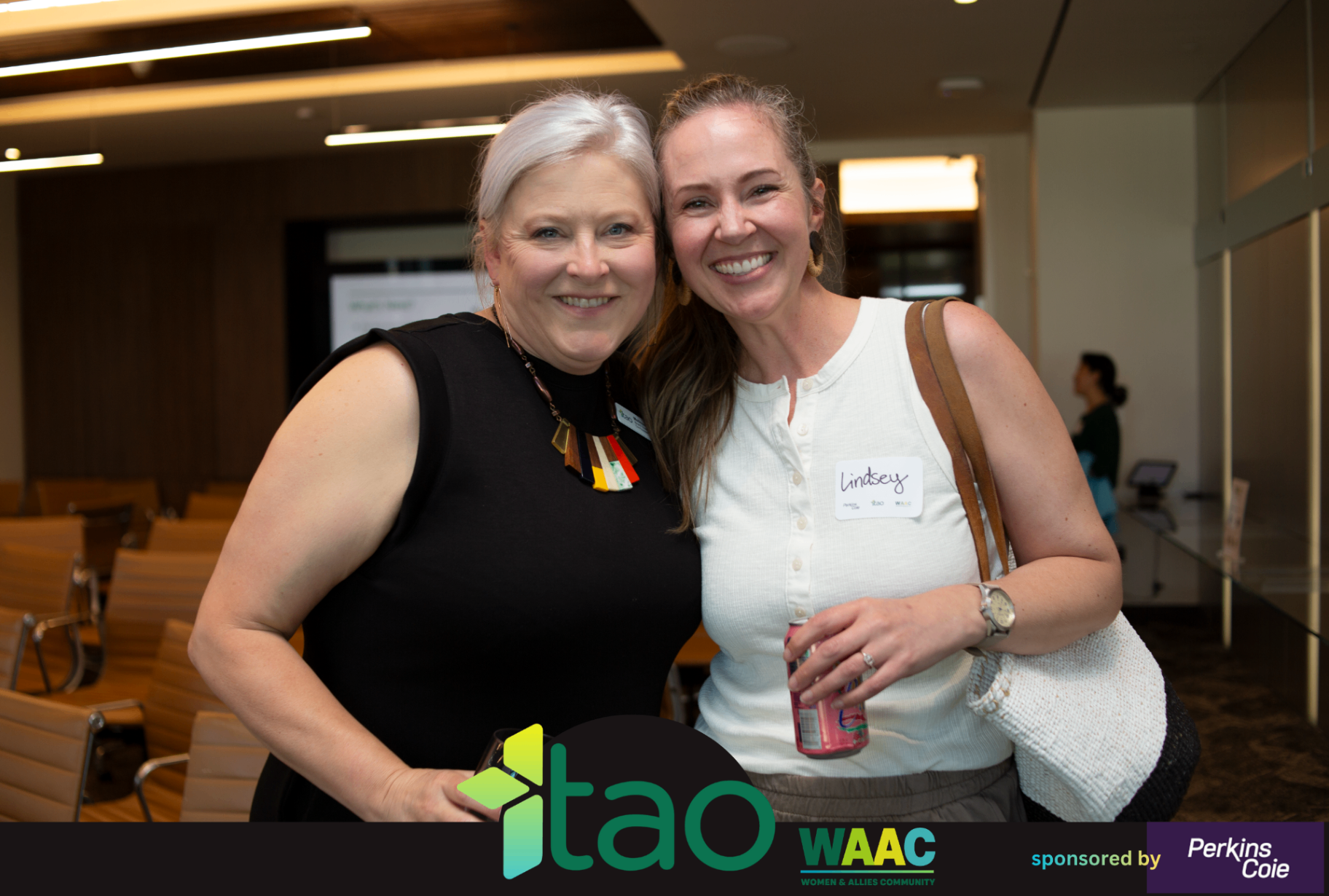 Two attendees posing together in a lounge area during the WAAC event.